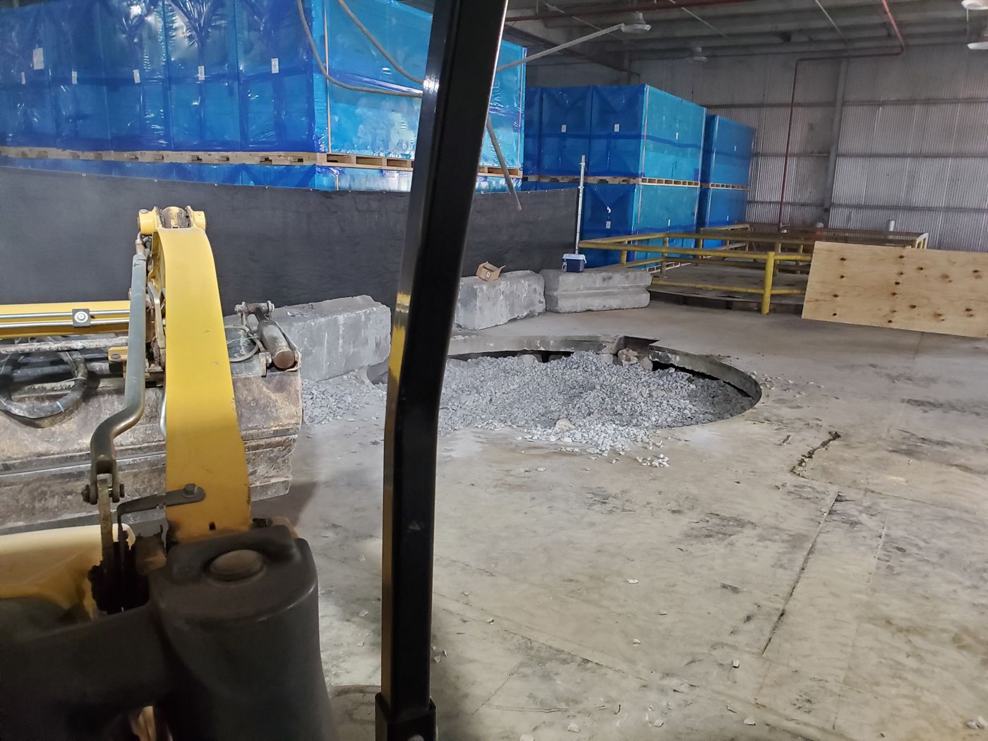 Excavator working inside a warehouse while inventory stays in place